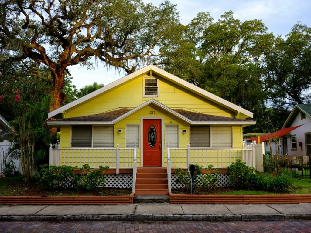 White and yellow cottage-style home with green trees