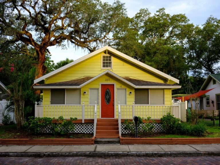 White and yellow cottage-style home with green trees